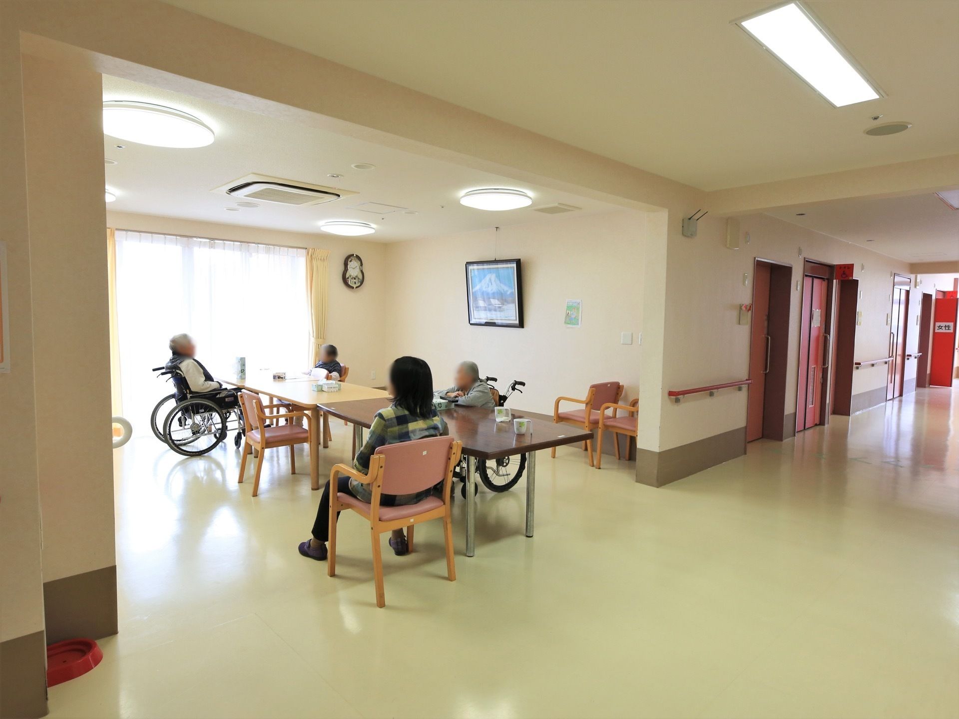 談話コーナーのすぐそばに男女それぞれのトイレが設置されている。壁には手すりがつけられ、歩行補助用として機能している。