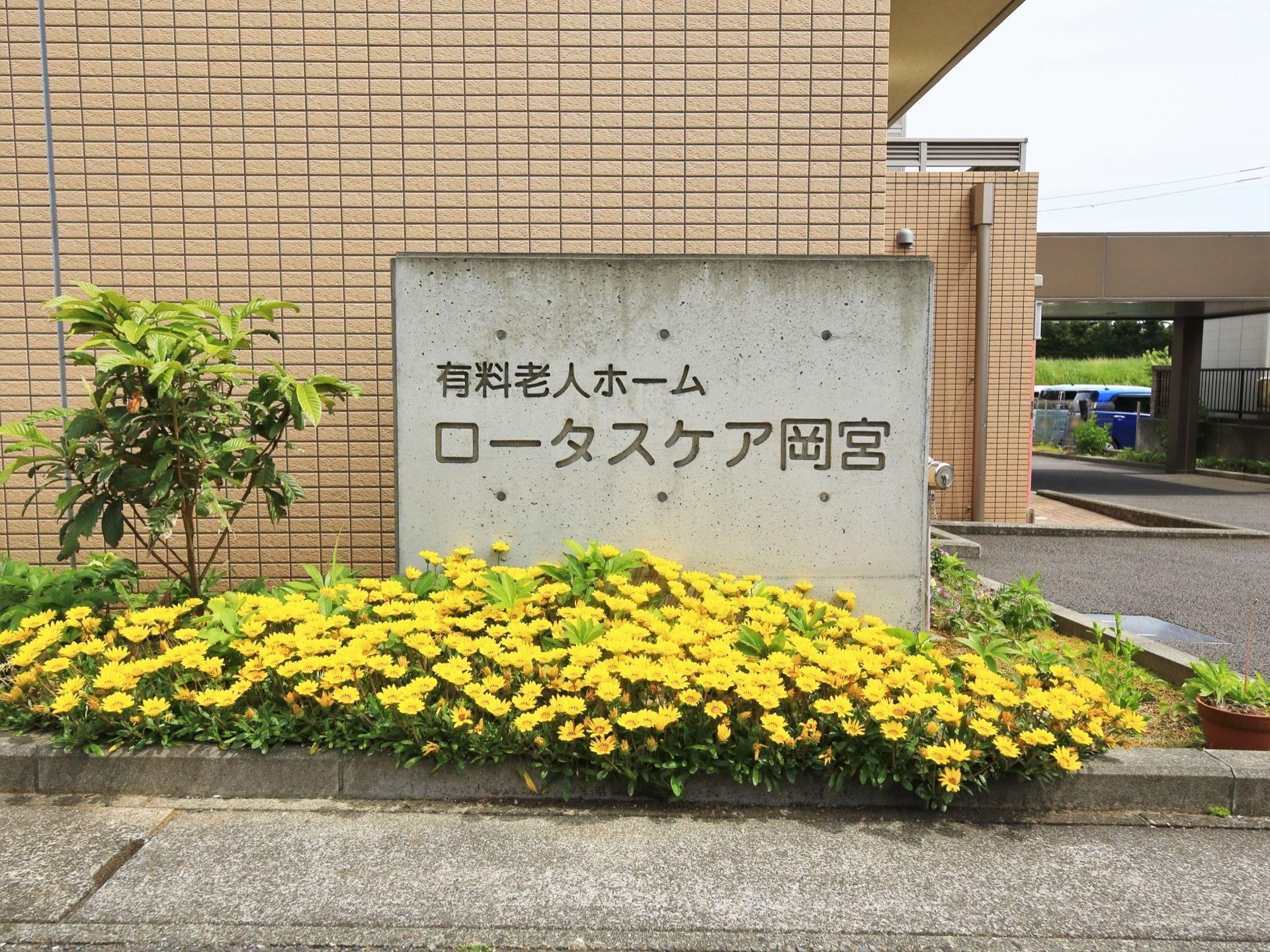 敷地の端っこにコンクリート造りの銘板が設置されている。周囲には木や花などが植えられ、華やかさを添えている。