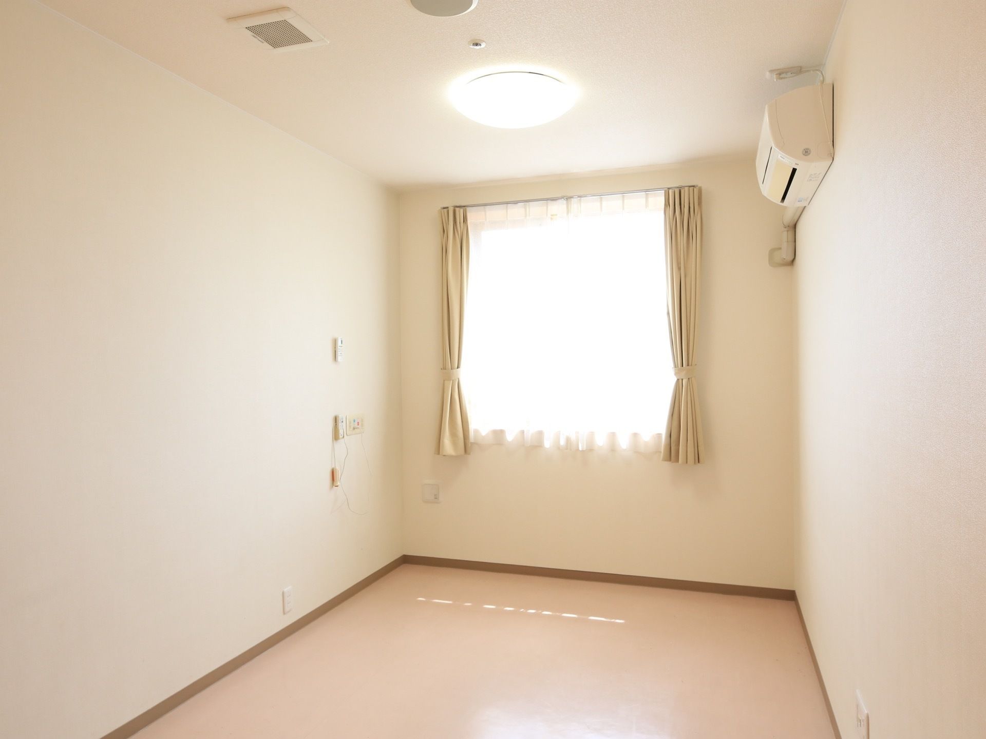 部屋の奥にある窓からは日が良く入り、白い壁に反射して部屋全体を明るく照らしている。電化製品のリモコンは一か所に集約して、壁に取りつけてある。