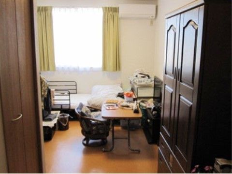大きな収納用の棚が設置された洋風タイプの居室である。室内の一角に備え付けられたベッドには、転落防止用の柵が取り付けられている。