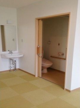 通路とトイレの間には段差のない設計であり、内部の壁には手すりが備え付けられている。また、トイレの入口手前には洗面台が設置されている。