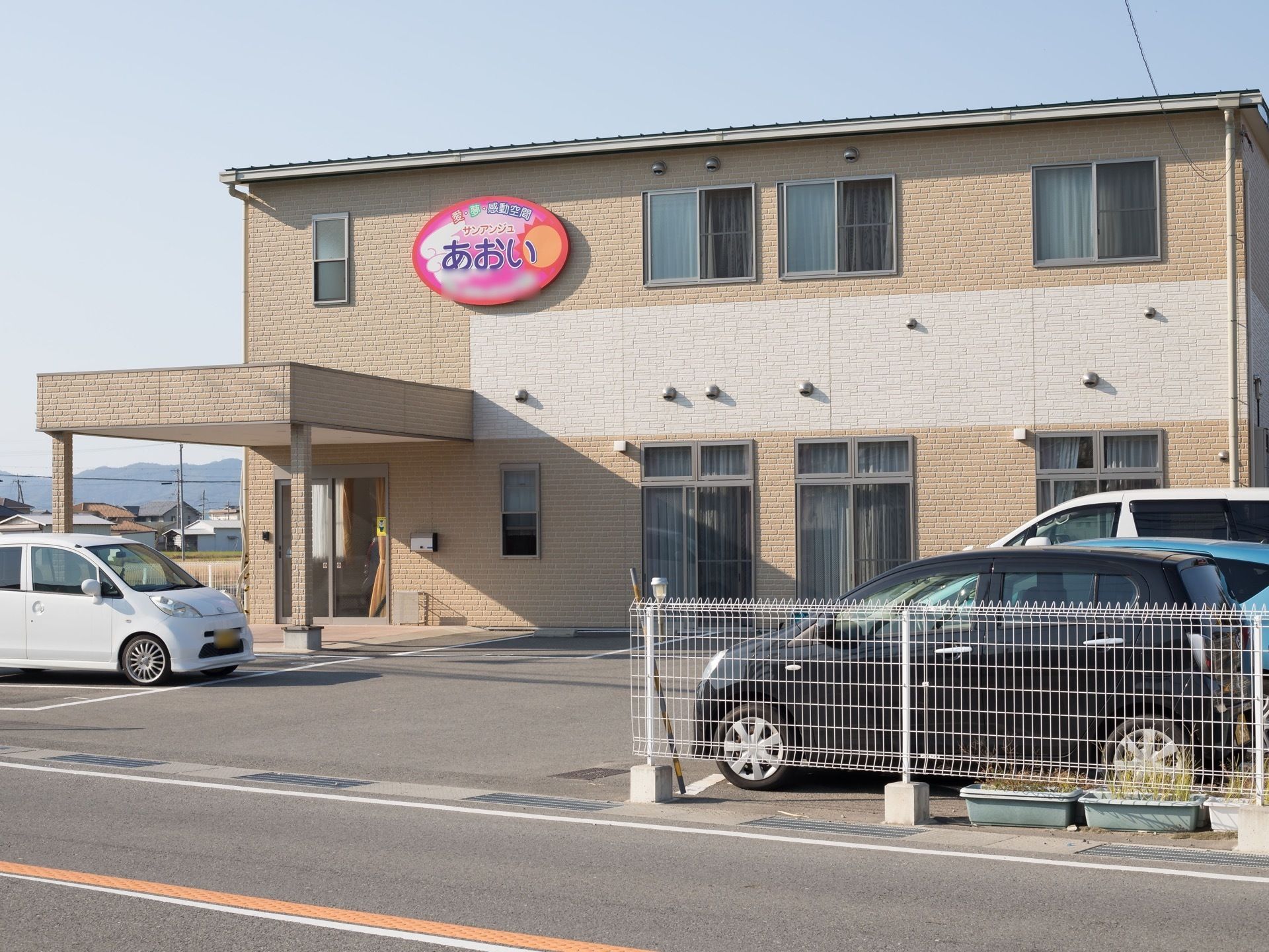 建物の外壁はレンガ風の化粧パネルが貼られている。玄関の上のあたりにはカラフルな施設看板が取りつけられている。