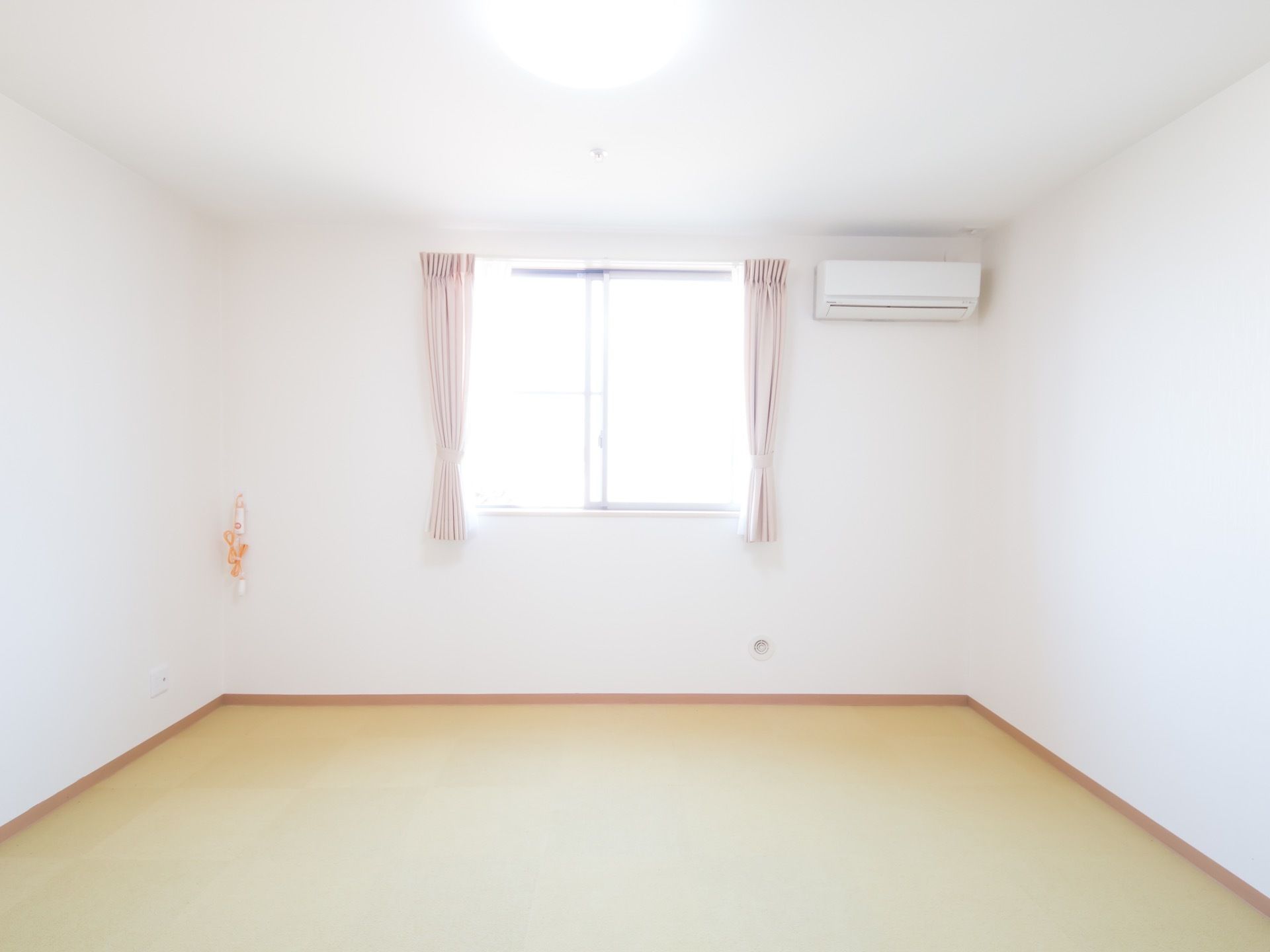 居室のベッドスペース。天井近くにはエアコンが取りつけられており、壁からはベッドで使うためのナースコールが出ている。