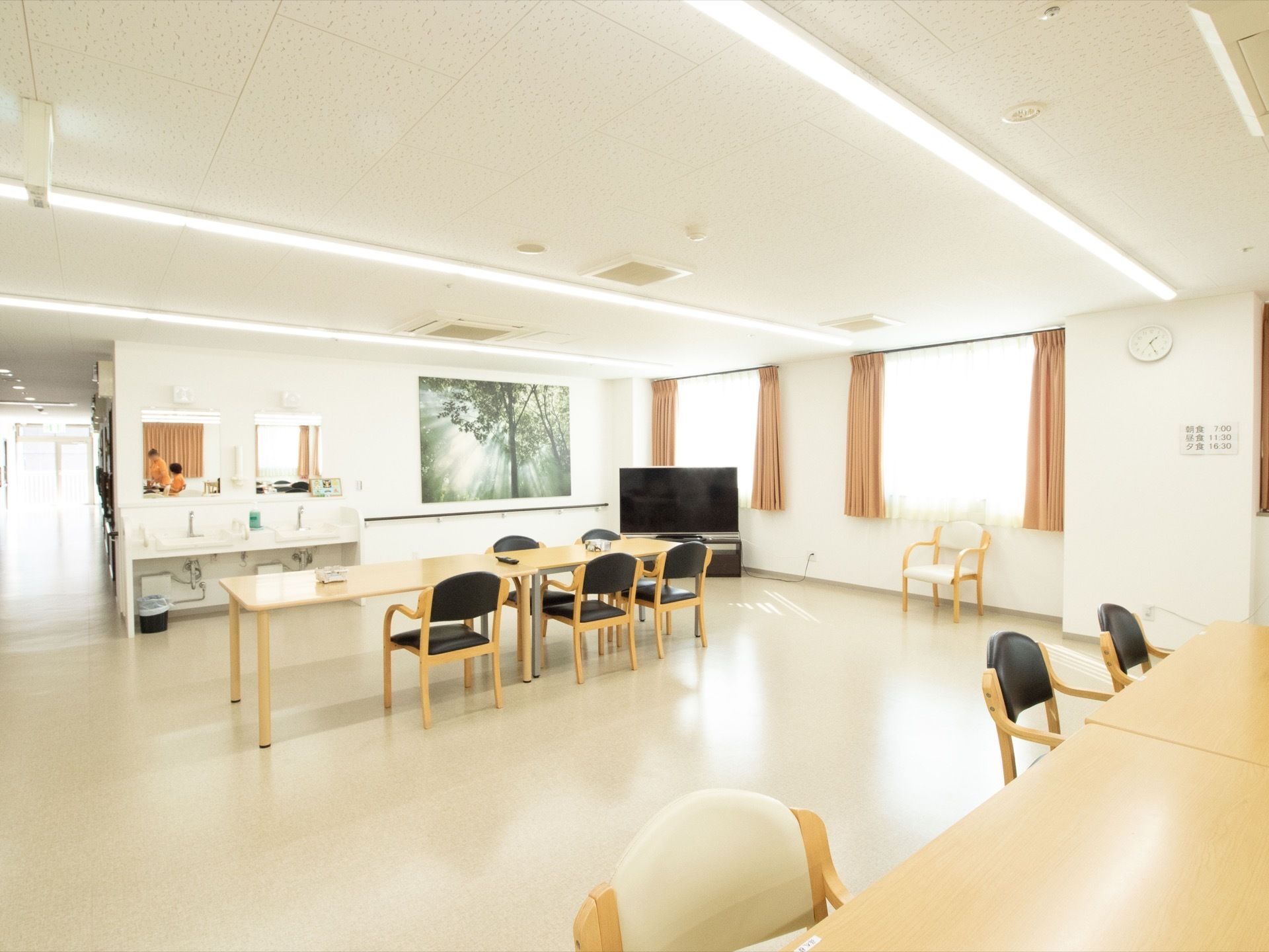 施設内にあるラウンジは広々としており、テーブルと黒い椅子がたくさん並んでいる。一角には、洗面台も設置されている。