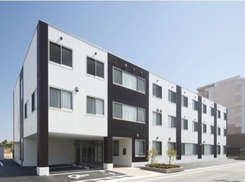 玄関付近に屋根のある駐車場を完備しているツートンカラーの3階建ての施設