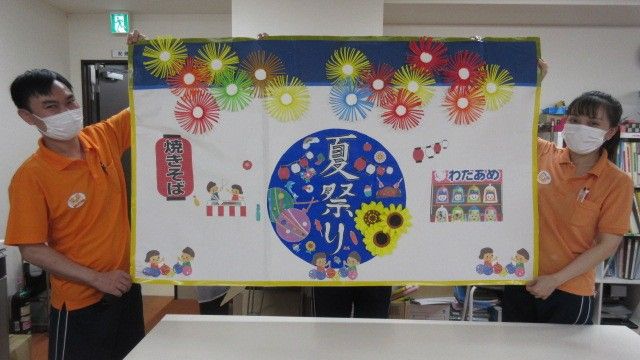 手作りの掲示板を持つスタッフ