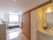 奥に大きな窓が付いたベッドの置いてある部屋がある洗面台が置かれた通路