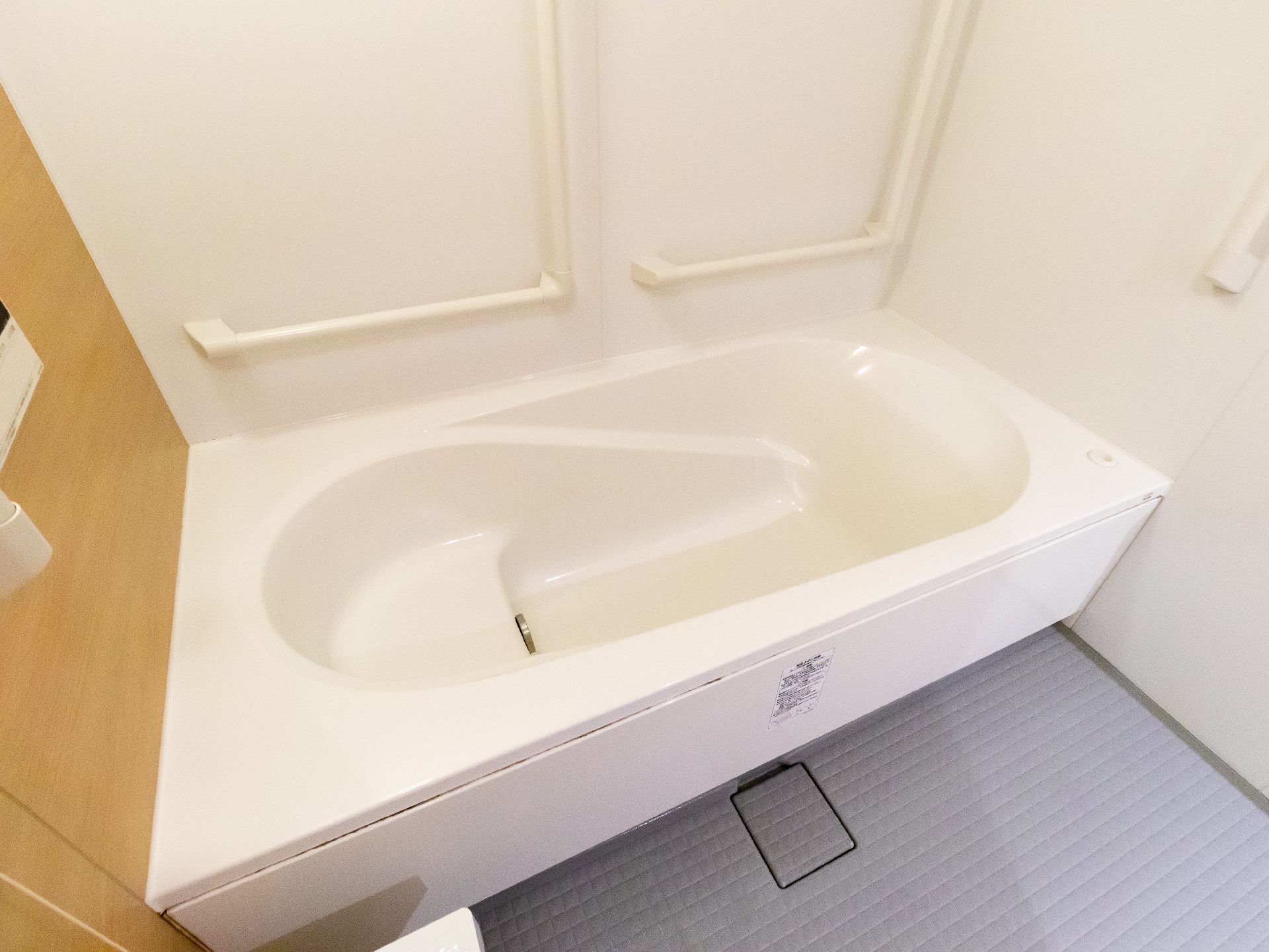 白い手すりが付いた白い壁の浴室