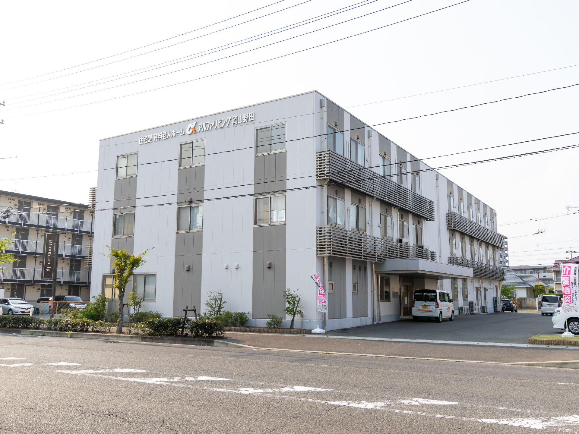道路沿いに立地している３階建てで白と灰色の外観の建物