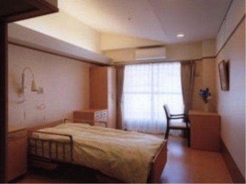 ベッドが中央にあり、奥にタンスやテーブル、椅子が置かれている居室