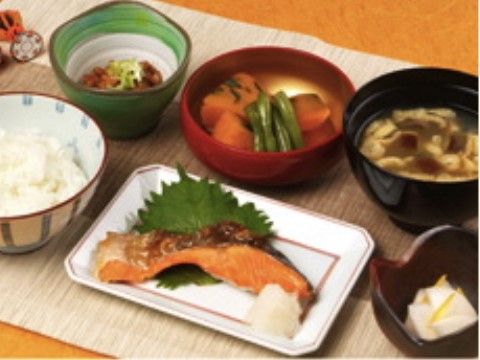 焼き魚が真ん中にあり、小鉢や汁物がある和食が並ぶ食卓