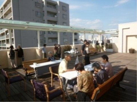 テラスに置かれたテーブルや椅子でくつろいだり、景色を眺めたりする入居者様たち
