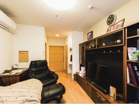 テレビや黒い大きな椅子が配置されたエアコン付きの居室