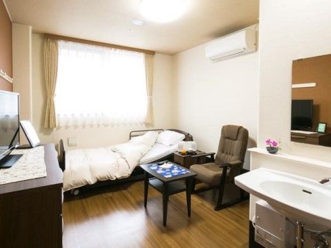 ベッドと座り心地のよい1人掛けソファが置かれ、手前に広い洗面台がある居室