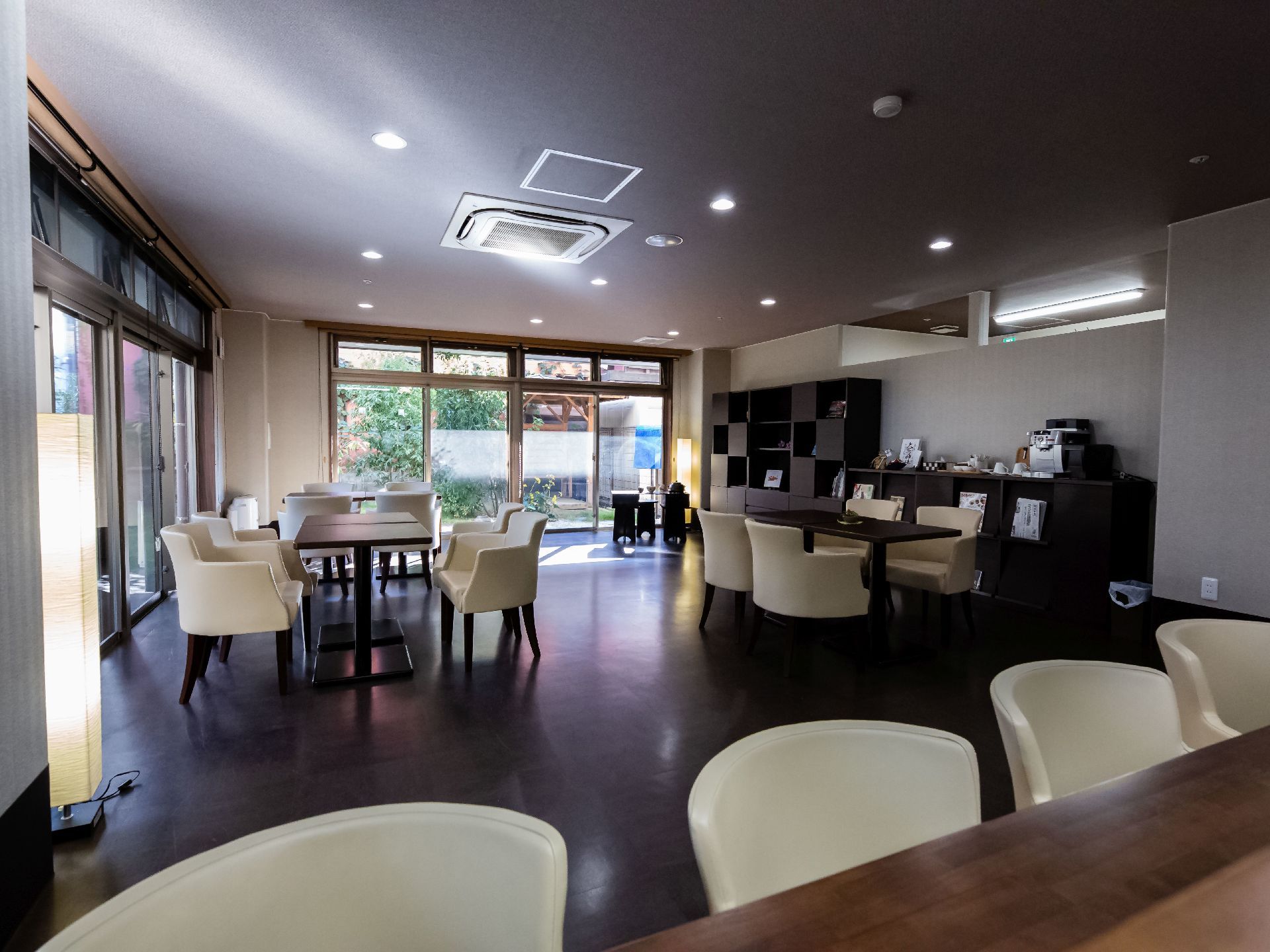 家具の配置にゆとりがある。本棚が壁に並んでおり、その上には雑貨やコップが置かれている。茶色と白で統一された洗練された雰囲気である。