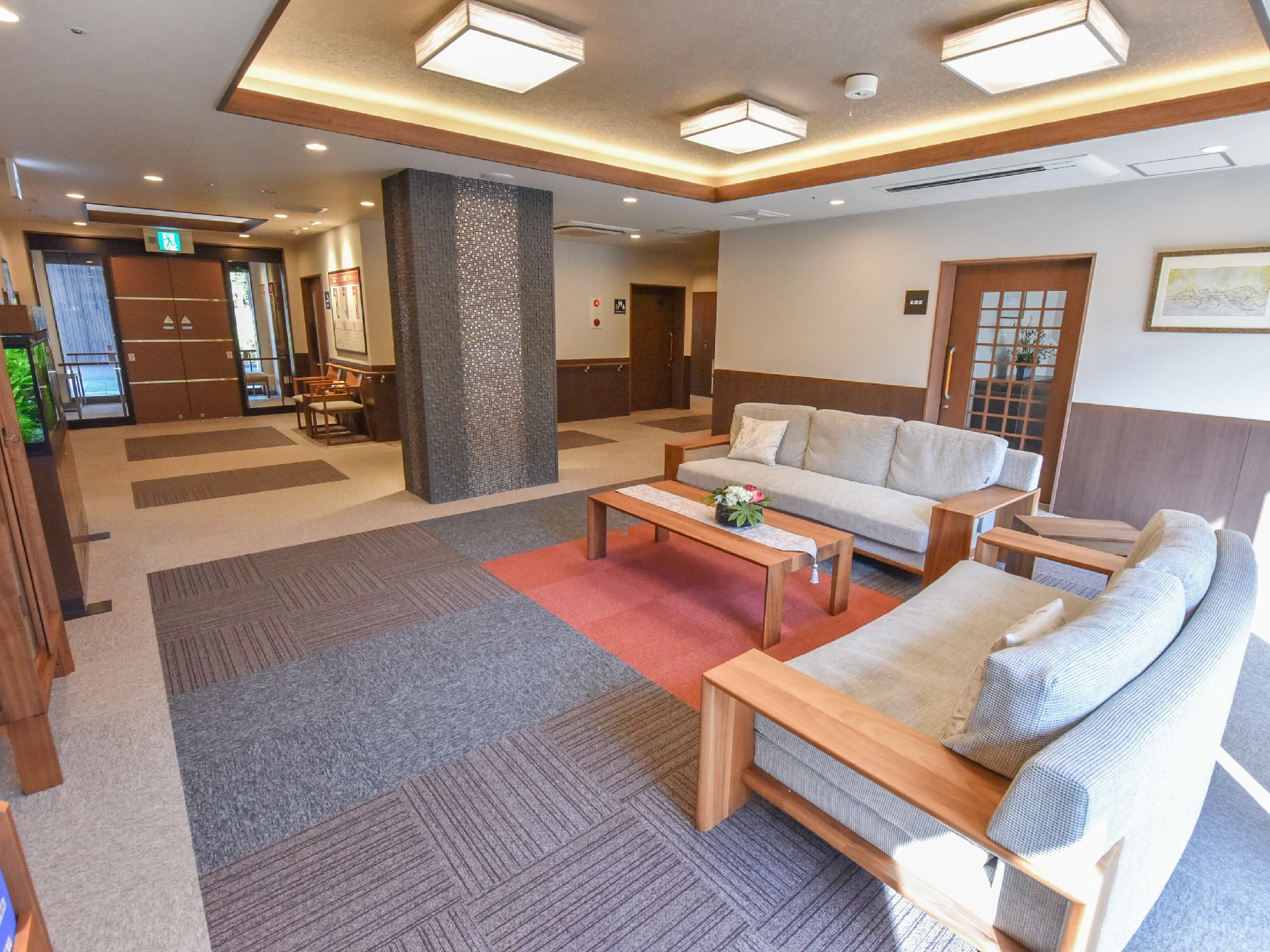 エントランスホールにはテーブルと2人用・3人用のソファーが置かれている。天井には和紙を使った和の照明が付けられている。