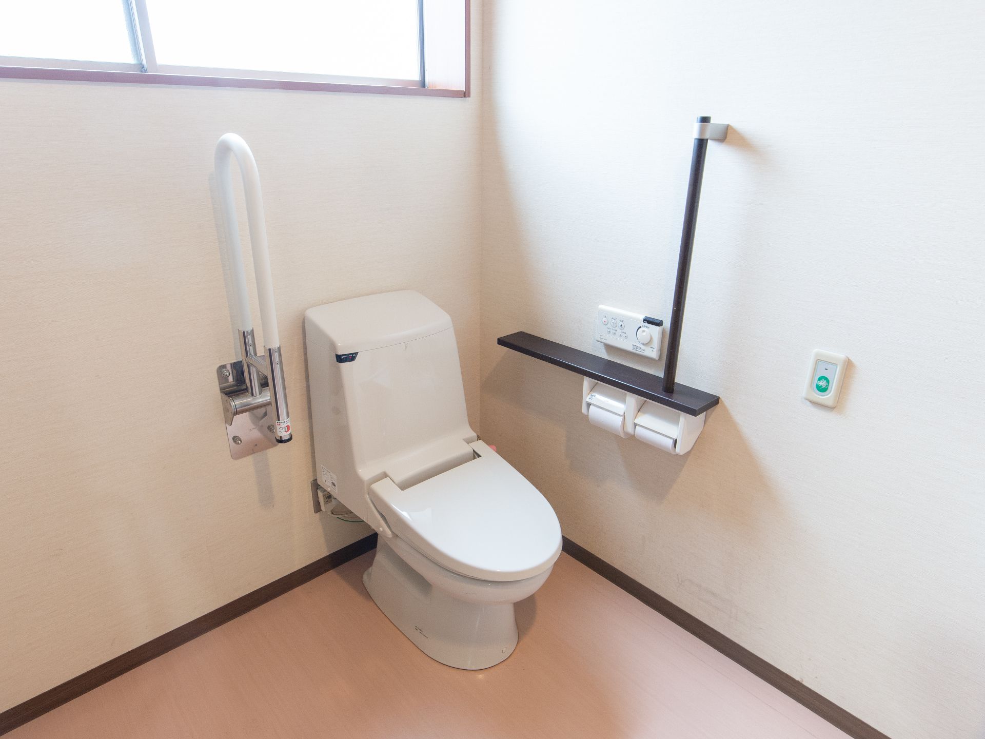 白を基調とした清潔感あふれるトイレである。バリアフリー仕様で、可動式の手すりやナースコールが設置されている。