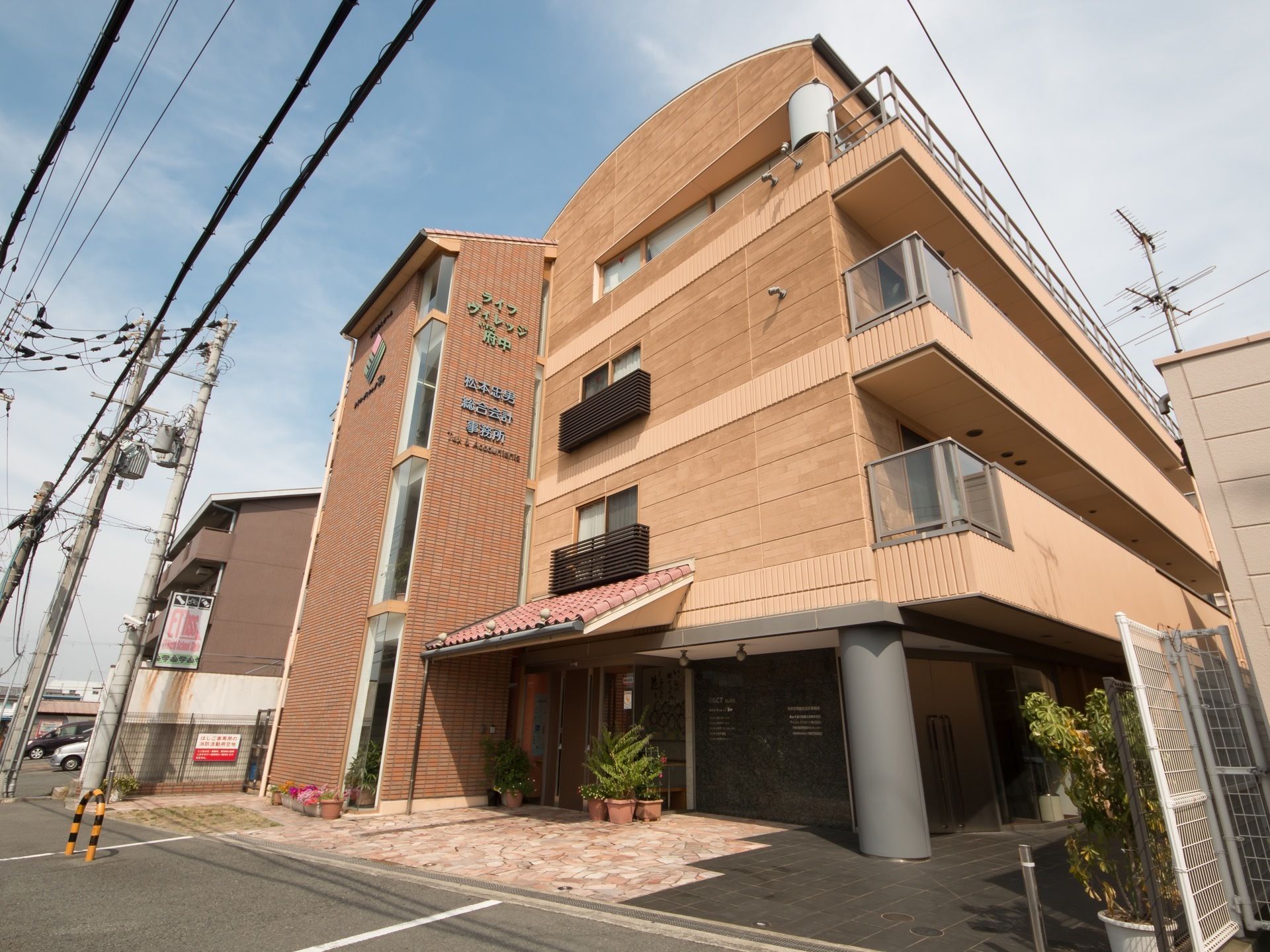 通りに面した場所に、４階建ての建物がある。茶色のタイルと木目を思わせるデザインが印象的。軒の部分は瓦屋根のようになっている。