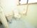 タイル敷きの洋式トイレがある。広々とした空間で、壁にはＬ字型の手すりとナースコールが設置されている。