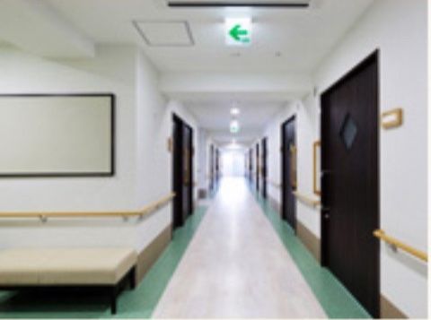 入居者様の居室が続く廊下は幅が広く、壁には手すりが設置されている。大きく開閉するスライド式のドアを通じて、居室への出入りが可能である。