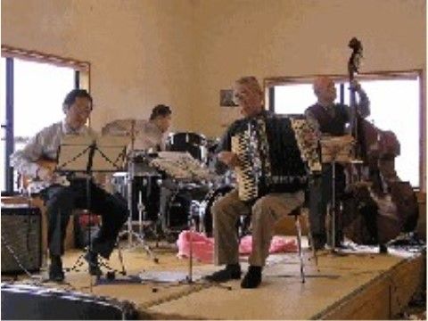 窓際に台を設置し、その上で楽器を演奏する4人の男性