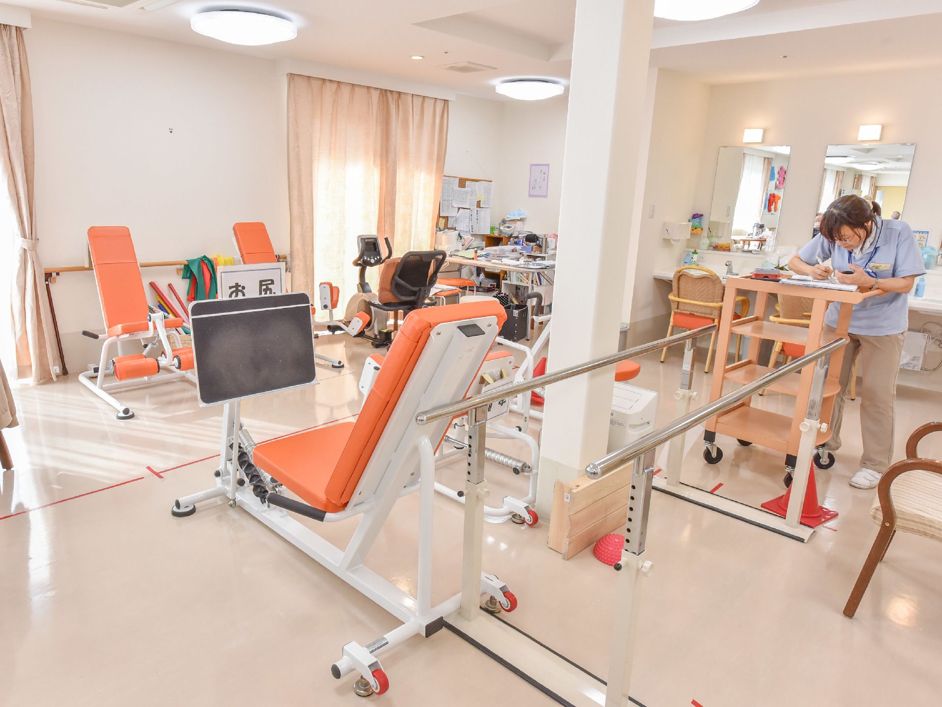 部屋には鏡付きの洗面台がある。近くには歩行訓練をする平行棒やお尻周りを鍛えることができる器具が置かれている。