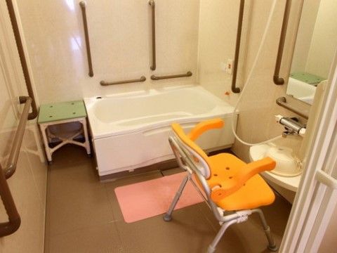 白いユニットバスが完備された浴室である。手すりや呼び出しブザーが設置されており、安全に配慮されている。