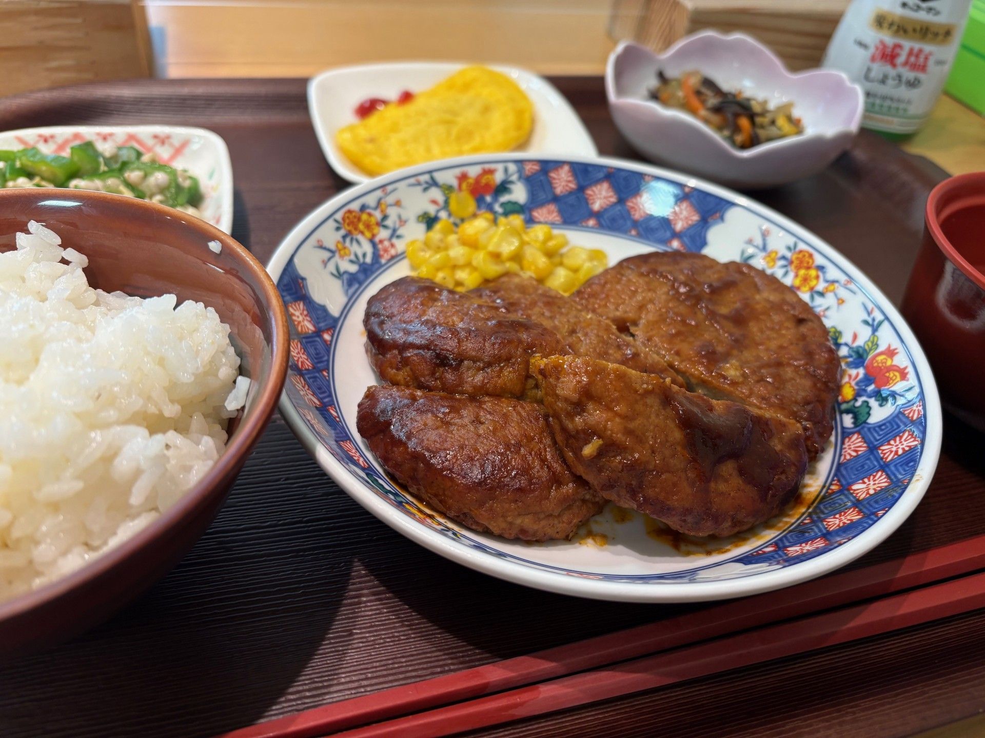野菜を飾ったメインの料理と、ご飯とお味噌汁のセット。ビールが添えられている。