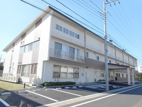 建物の前面から裏側にかけて、屋根が斜めに付いている。前面には駐車場を配置して、車止めのブロックもある。