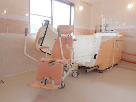 介護浴槽と浴室用車椅子が完備された、タイル張りで清潔感のある浴室