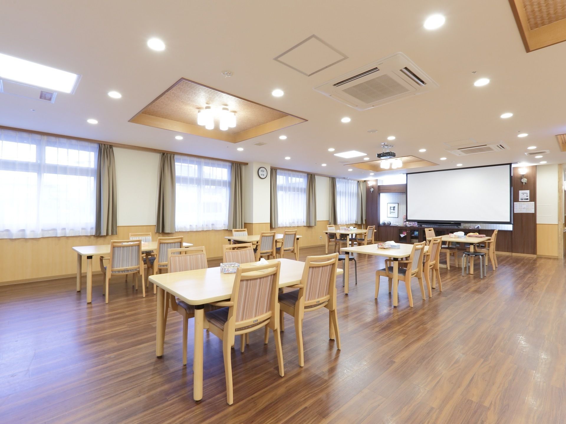 食堂の壁際に、白いスクリーンが掛けられている。天井にプロジェクターの機器が取り付けられており、画像を映すことができる。