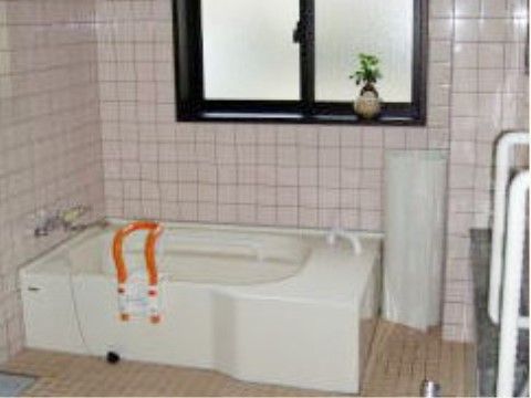 手すりや入浴グリップなどの安全対策が施された、タイル張りで清潔感のある浴室