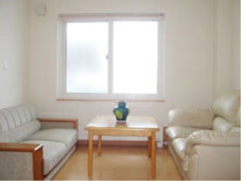 白い壁に大きな窓があり、明るい部屋である。テーブルを挟んでソファーが設置してある。テーブルには青い花瓶が置いてある。