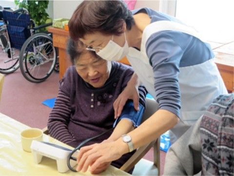 高齢者の血圧測定を行う介護スタッフ