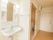 居室には専用の洋式トイレと鏡と棚の付いた洗面台がある。部屋の壁は白で統一されていて清潔感がある。入口は大きな引き戸の扉になっている。