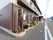 外壁の色に合わせた落ち着いたデザインの看板が設置されている。建物に沿って花壇があり、数種類の植物が植えられている。