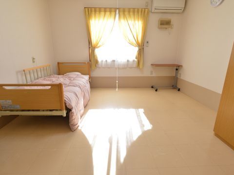 入居者が過ごす個室には手すり付きのベッドが置かれていて、広々としている。窓からは日光が入っていて、部屋全体が明るい。