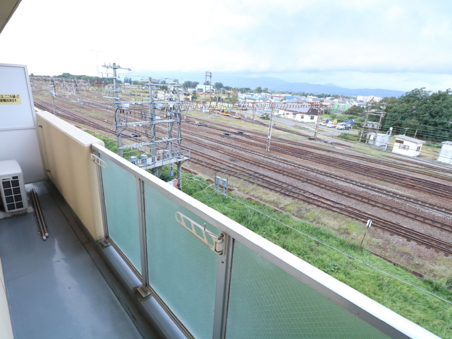 ベランダからは線路や周辺の町並み、大きな川も見渡せ、広大な景色が広がっている。また、洗濯物が干せるようにもなっている。