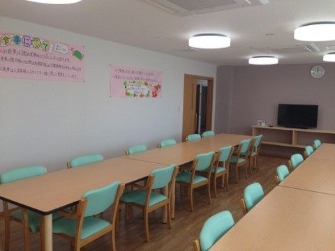 テーブルと緑の椅子が複数設置された食堂
