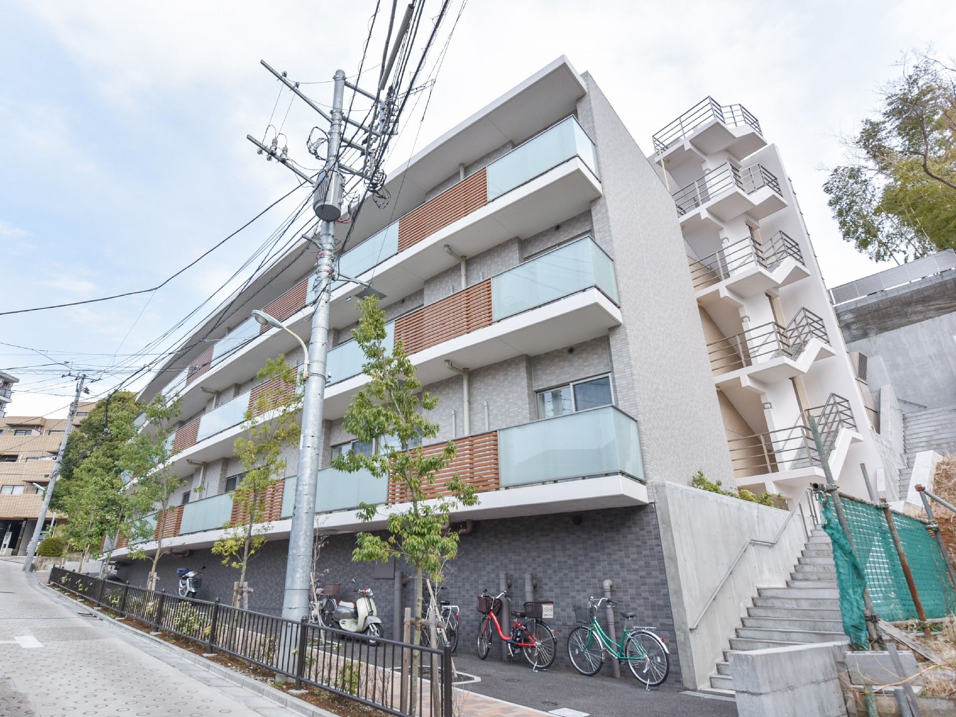 坂道に建てられたお洒落な外観の当施設。駐輪場も設けている。