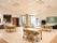 キャスターが付いた可動式のテーブルセットが並べられている。大型の液晶テレビと、自動販売機が置かれている。