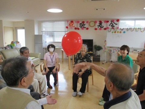 円になって椅子に座り、風船を使ったレクリエーションを楽しむ入居者様とスタッフ