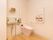 薄いピンク色のトイレに温水洗浄便座が取りつけられている。壁に折り畳み式のものと固定式の手すりが設置されている。