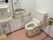 壁に手すりが取り付けてあるトイレで、ペーパーホルダーの上部が棚になっている。そこにはベルが置いてある。