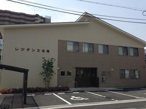 ベージュを基調とした落ち着いた色調の2階建ての建物である。目の前の駐車場から、スムーズにお入りいただける。