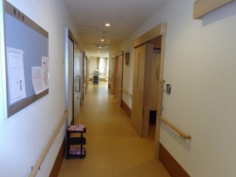 フローリングの明るい廊下には手すりが備えられている。掲示板を使って、皆様への連絡事項をお知らせしている。