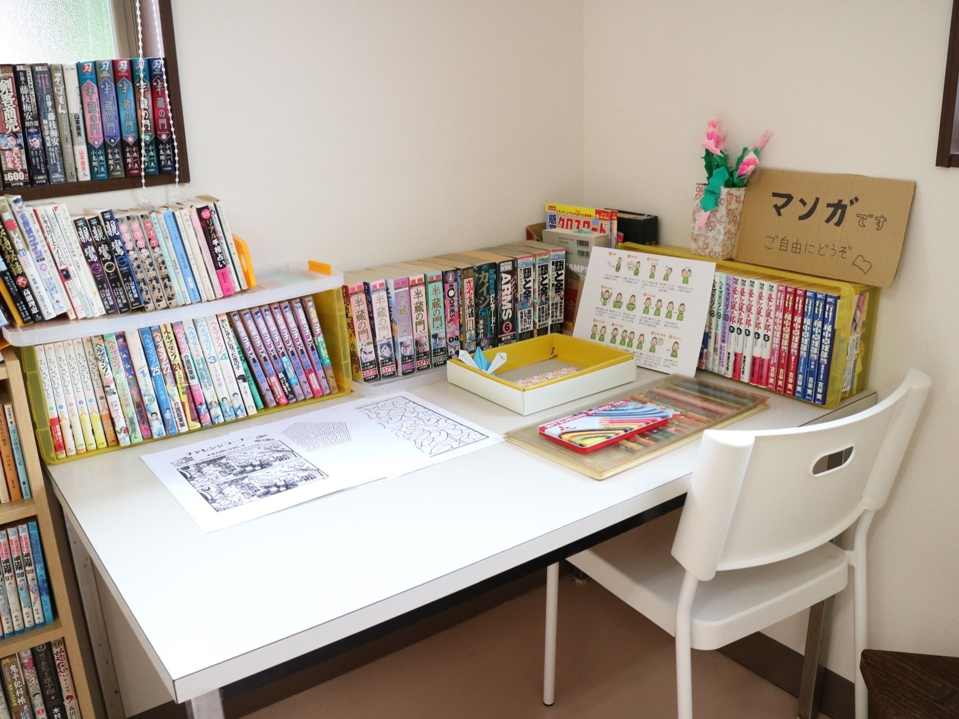 さまざまなジャンルが取り揃えられている漫画スペースである。フロア隅には、白い椅子と机が配置されている。