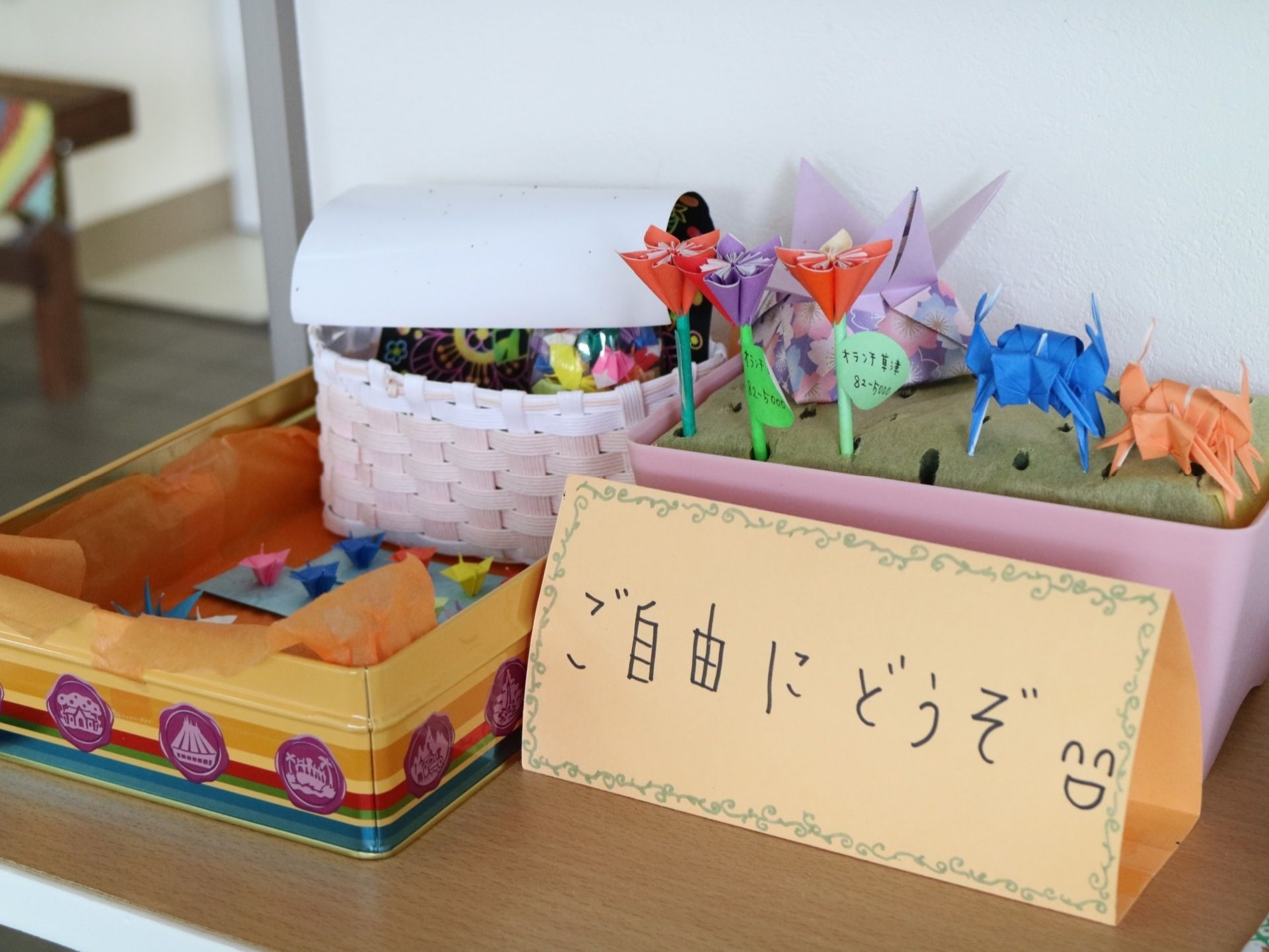 折り紙で作られた色とりどりの作品が、机の上に置かれた缶やカゴに入れられており、自由にもらえるようになっている。