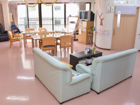 ピンク系の床が明るい雰囲気の共有フロア。広々とした空間にテーブルや椅子の他、ソファセットが置かれている。