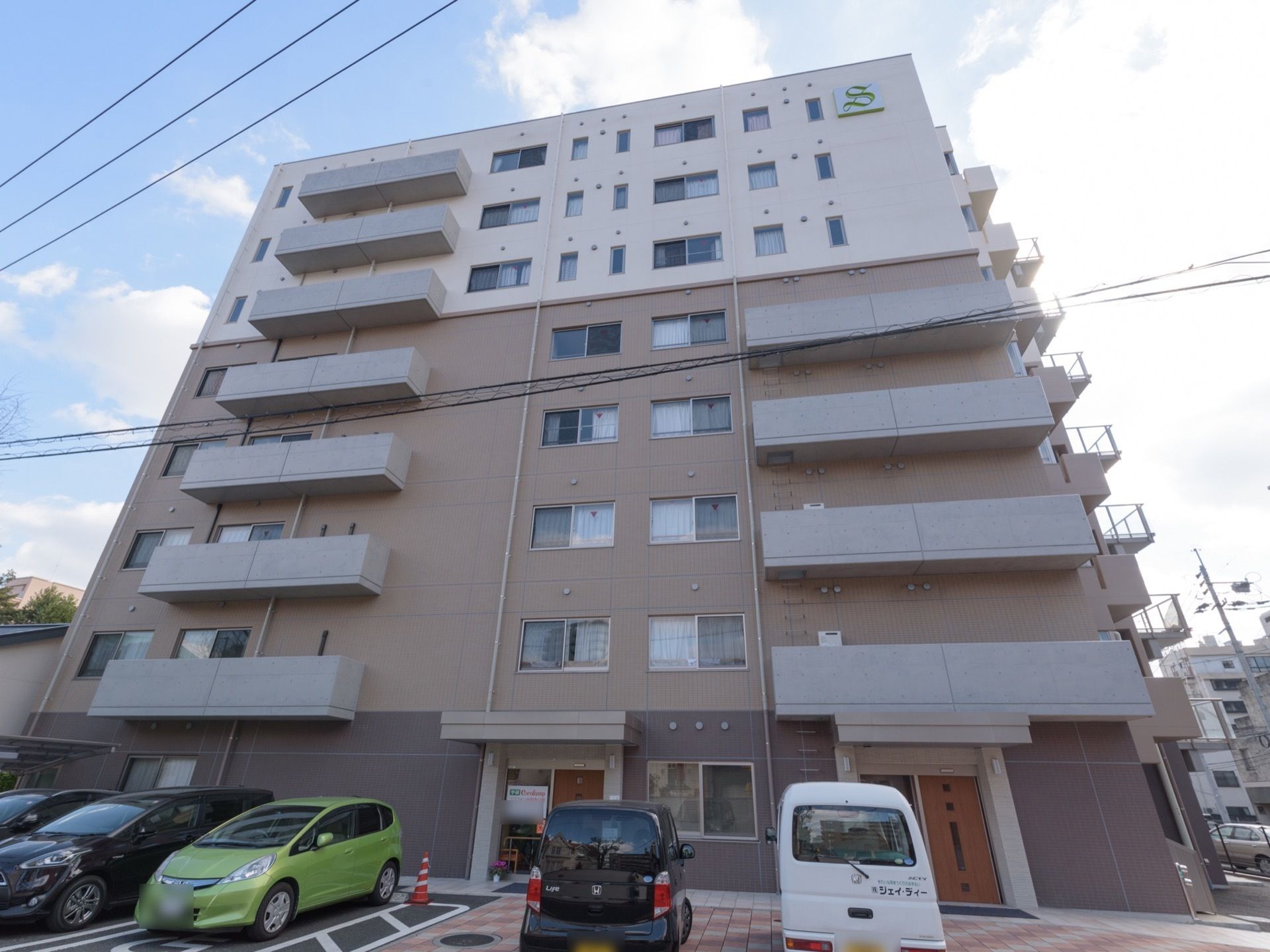 8階建ての落ち着いた雰囲気の建物で、ブラウンが基調の外壁になっている。施設の前は駐車場になっている。